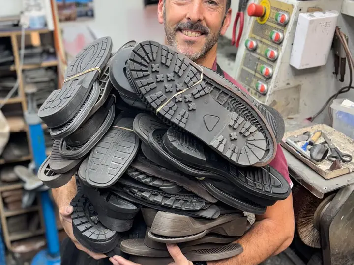 Alberto con una montaña de suelas nuevas de goma en el taller
