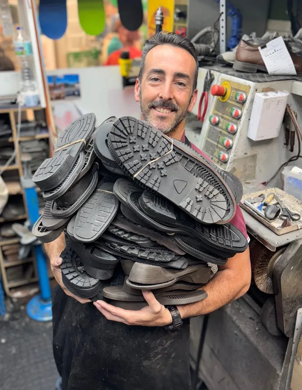 Alberto, maestro zapatero de Zapaexpress, sujeta una montaña de suelas nuevas en su taller