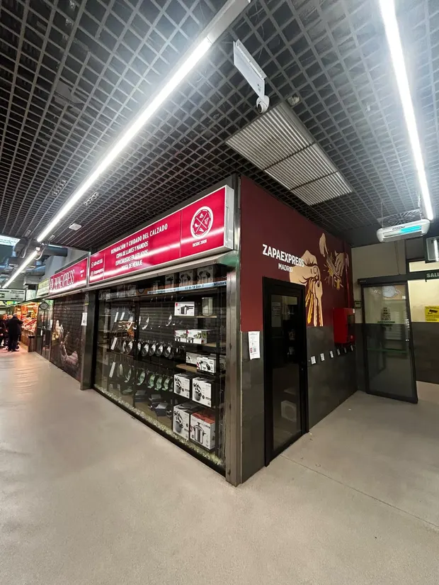 Fachada del puesto de Zapaexpress en el mercado, con el rótulo rojo y el escaparate de menaje