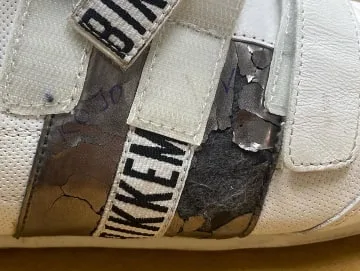 Zapatilla blanca de piel con las tiras de velcro agrietadas y despegadas